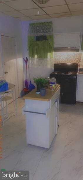 kitchen featuring white cabinets, a drop ceiling, and light tile patterned floors