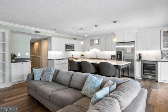 living room featuring ornamental molding, sink, beverage cooler, a textured ceiling, and dark hardwood / wood-style floors