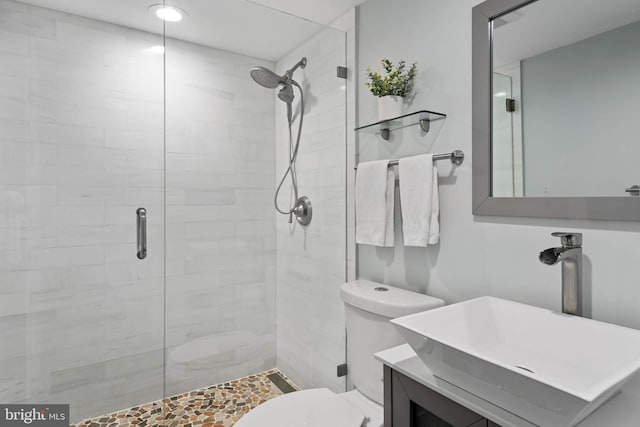 bathroom with vanity, toilet, and a shower with door