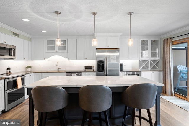 kitchen featuring stainless steel appliances, a center island, and decorative light fixtures