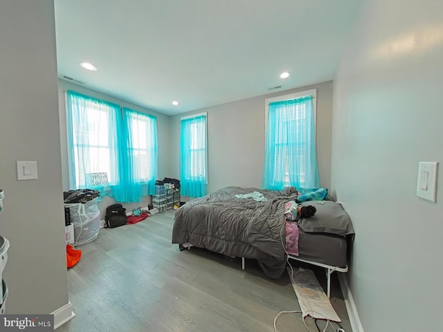 bedroom with multiple windows and hardwood / wood-style flooring