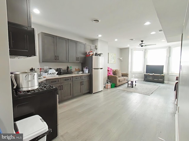 kitchen with light wood-type flooring, black appliances, and ceiling fan