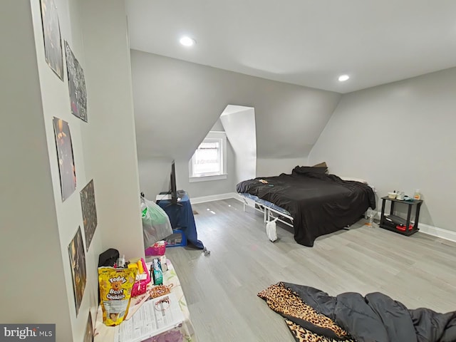 bedroom featuring light hardwood / wood-style flooring, lofted ceiling, and a fireplace