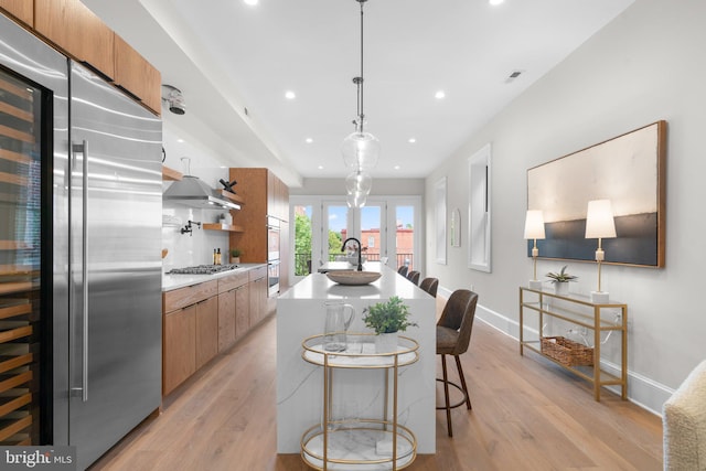 kitchen with a breakfast bar, sink, hanging light fixtures, appliances with stainless steel finishes, and a kitchen island with sink