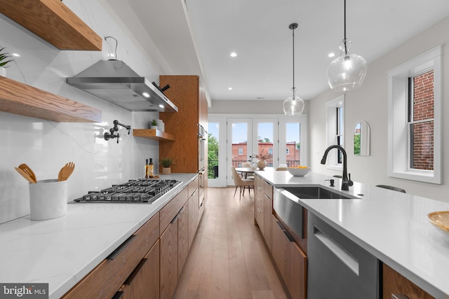 kitchen with pendant lighting, sink, backsplash, stainless steel appliances, and french doors