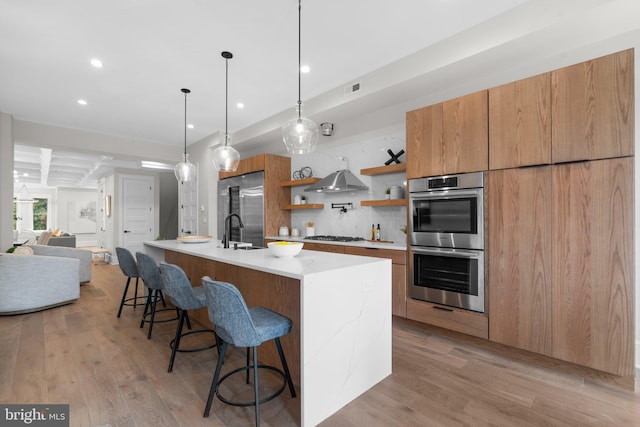 kitchen featuring appliances with stainless steel finishes, a large island, light hardwood / wood-style floors, and sink