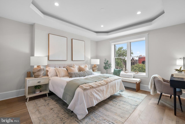 bedroom with hardwood / wood-style flooring and a tray ceiling