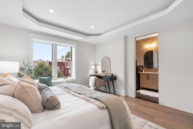 bedroom featuring hardwood / wood-style floors and a tray ceiling