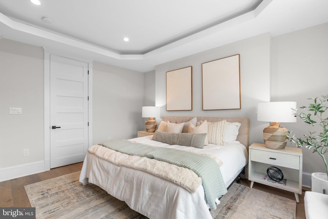 bedroom with hardwood / wood-style flooring and a raised ceiling