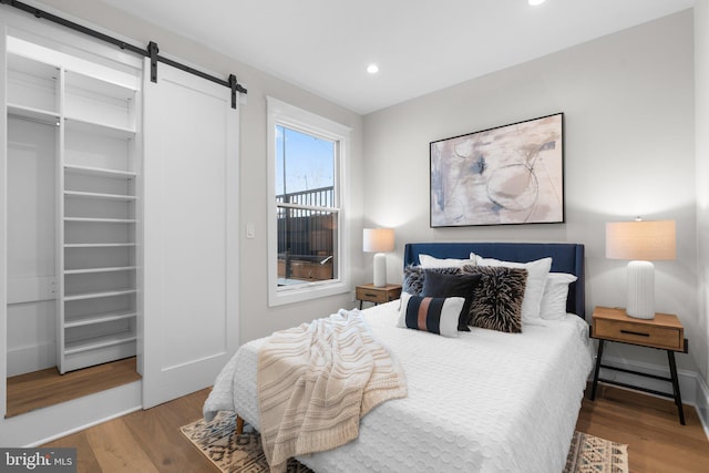 bedroom featuring a barn door and hardwood / wood-style floors