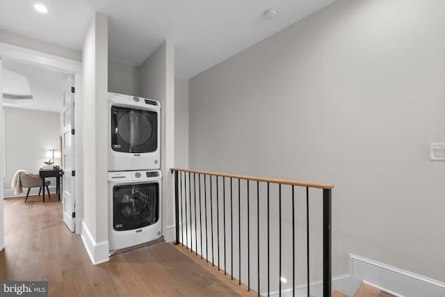 clothes washing area featuring stacked washer / drying machine and hardwood / wood-style floors