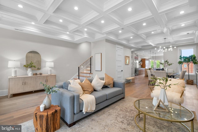 living room with coffered ceiling, a notable chandelier, beam ceiling, and light wood-type flooring