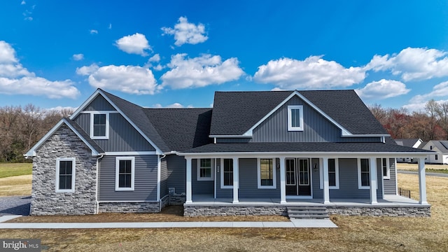 view of front of home with stone siding, a porch, board and batten siding, and roof with shingles