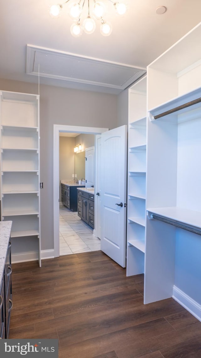 walk in closet with dark wood-style floors, attic access, and a chandelier