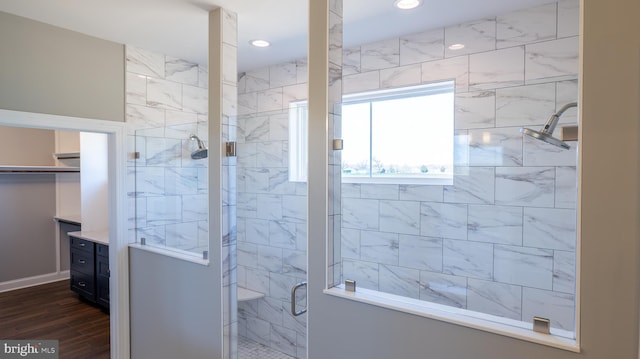 full bath with a walk in closet, a shower stall, recessed lighting, and wood finished floors