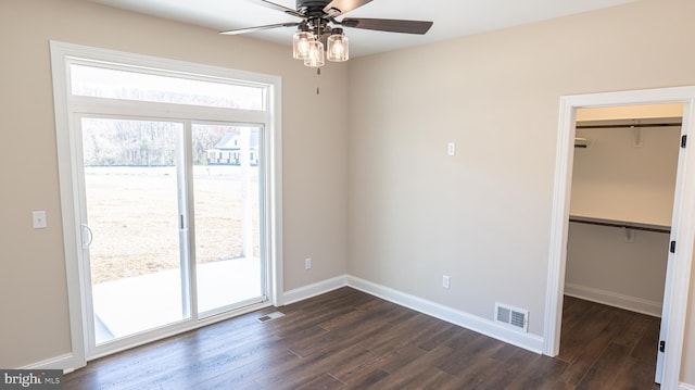 interior space with dark wood-style flooring, a walk in closet, visible vents, and access to exterior