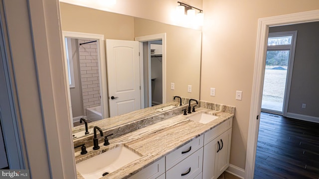 bathroom with double vanity, baseboards, a sink, and wood finished floors