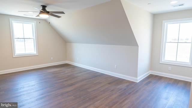 bonus room with dark wood-style floors, visible vents, a ceiling fan, vaulted ceiling, and baseboards