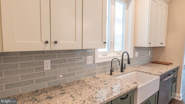 kitchen with tasteful backsplash, a sink, light stone countertops, and white cabinets