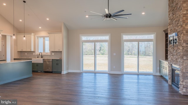 unfurnished living room with a stone fireplace, a sink, dark wood finished floors, and recessed lighting