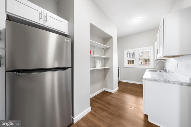 kitchen with built in features, stainless steel refrigerator, sink, white cabinets, and dark wood-type flooring