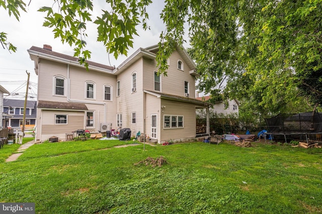 back of property with a yard and a trampoline