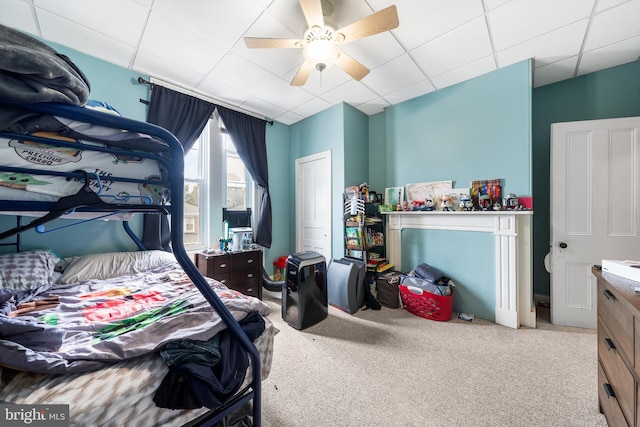 carpeted bedroom with a paneled ceiling and ceiling fan