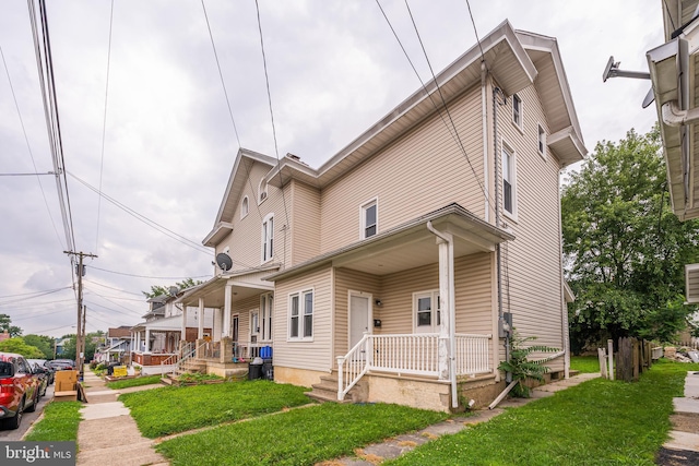 view of side of property featuring a yard and covered porch