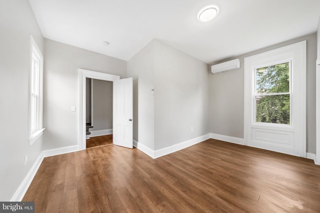 empty room with dark hardwood / wood-style flooring and a wall mounted AC