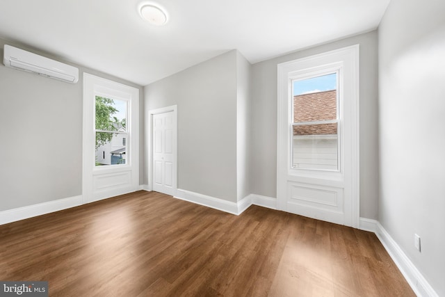 unfurnished room featuring an AC wall unit and dark wood-type flooring