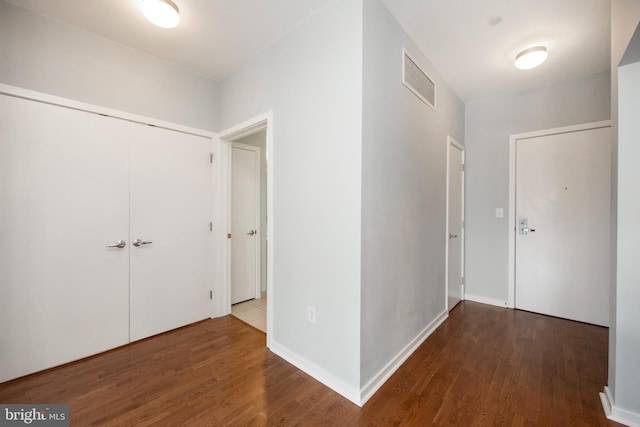 hall with wood finished floors, visible vents, and baseboards