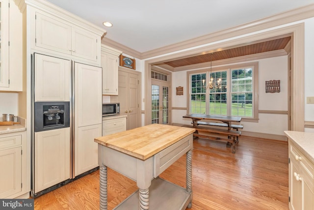 kitchen with pendant lighting, crown molding, paneled refrigerator, a chandelier, and light wood-type flooring