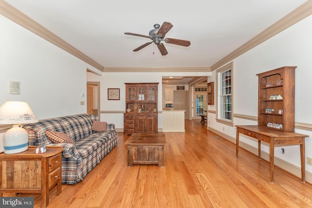 living room featuring ornamental molding, ceiling fan, and light wood-type flooring