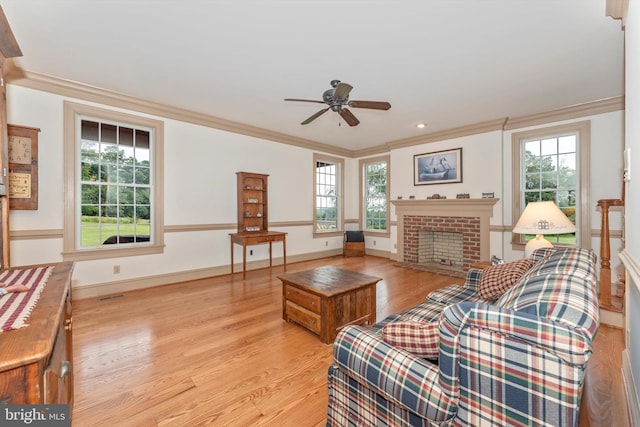 living room featuring a brick fireplace, crown molding, and light hardwood / wood-style flooring