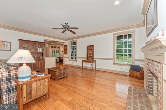 living room featuring a brick fireplace, ornamental molding, light hardwood / wood-style floors, and ceiling fan