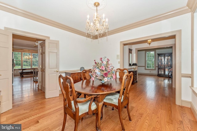 dining room featuring ornamental molding, light wood-type flooring, and an inviting chandelier