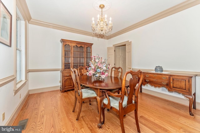 dining room with crown molding, light wood-type flooring, and a notable chandelier