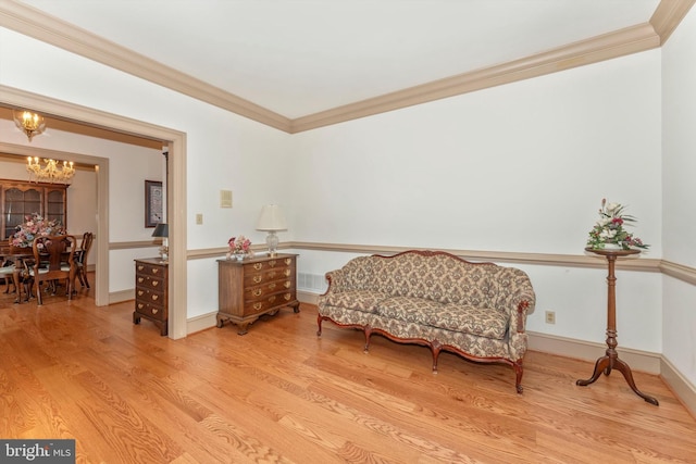 sitting room with a notable chandelier, crown molding, and light hardwood / wood-style flooring