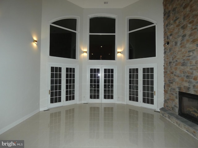 unfurnished living room featuring a stone fireplace and light tile patterned floors