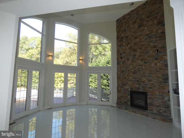 doorway featuring a stone fireplace, plenty of natural light, and a high ceiling