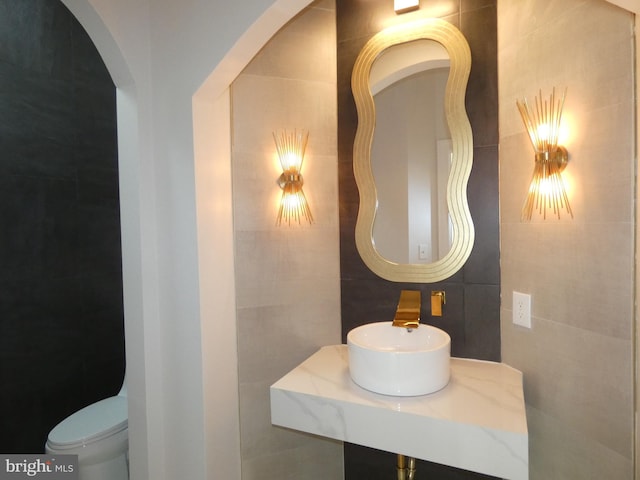 bathroom with tile walls, sink, and toilet