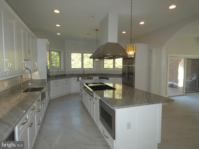 kitchen featuring white cabinetry, island range hood, decorative light fixtures, and a center island