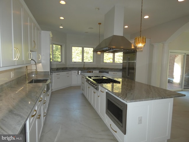 kitchen with a center island, built in appliances, white cabinets, island exhaust hood, and decorative light fixtures