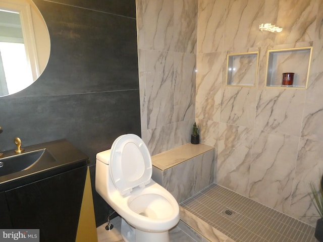 bathroom featuring vanity, a tile shower, and toilet