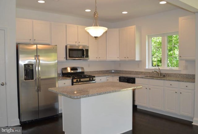 kitchen with white cabinets, a kitchen island, appliances with stainless steel finishes, decorative light fixtures, and sink