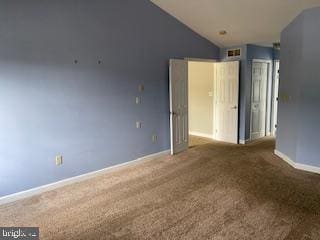 carpeted empty room featuring lofted ceiling