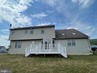 back of property featuring a yard and a wooden deck