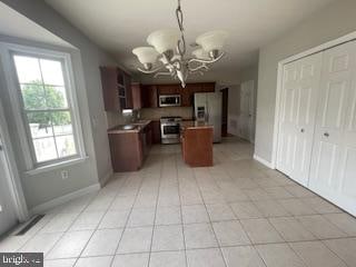 kitchen with light tile patterned flooring, stainless steel microwave, refrigerator with ice dispenser, an inviting chandelier, and stove