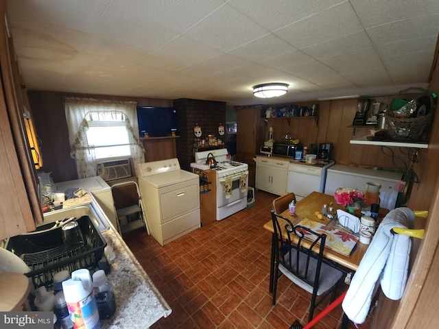 kitchen with brick wall, washing machine and clothes dryer, white appliances, and wooden walls