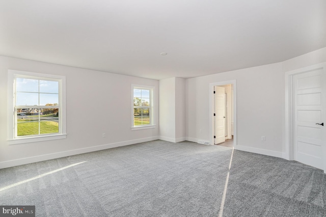 unfurnished bedroom featuring multiple windows, connected bathroom, and carpet